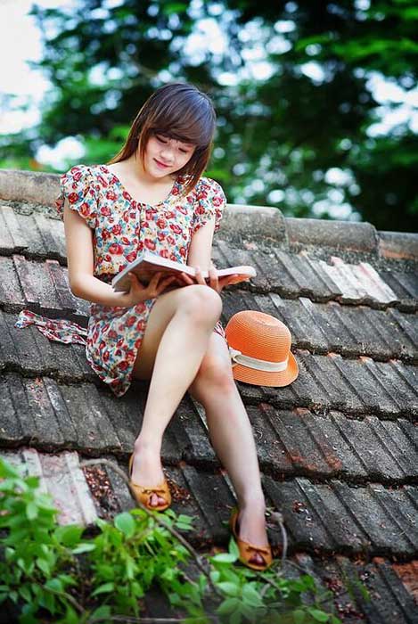 Young girl reading book on the house roof