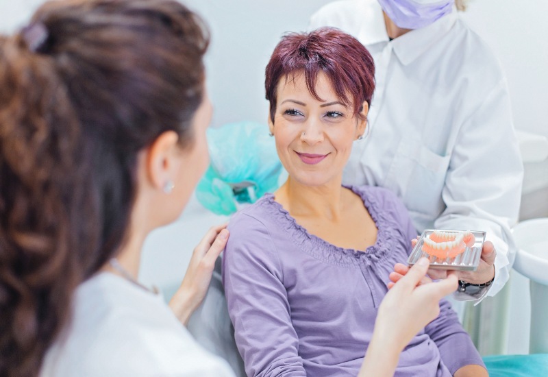 Dentist showing a dental model during a dental implant consultation in Southfield, MI