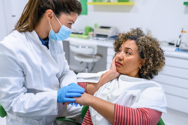 Patient holding jaw while consulting dentist for emergency dental care in Southfield, MI